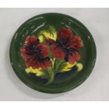 Moorcroft Pottery Hibiscus pattern circular plate with green ground, 22cm dia.
