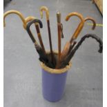 Pottery umbrella stand containing nine walking sticks and umbrellas and a riding crop