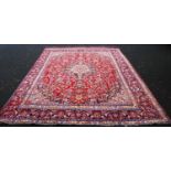 Isfahan style carpet with central medallion, all over floral pattern, spandrels, red ground, and