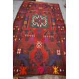 Kilim with central panel over red ground, geometric pattern, and deep border, 320cm x 183cm.