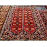 Turkish carpet with two panels with row of seven diamonds and stars over red ground, spandrels and