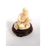 Japanese ivory carved figure of a seated man with corn by his side, signed to the base, 9.5cm high.