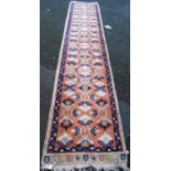 Turkish runner with three rows of foliate cruciforms over pink ground, and blue border, 434cm x