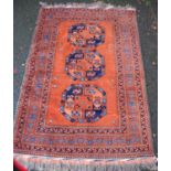 Persian rug with three central medallions over orange ground, and border, 192cm x 126cm.