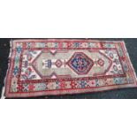 Persian rug with central medallion, opposing arrows over cream ground, and triple border, 180cm x