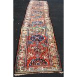 Persian runner with ten medallions over faded red ground, and triple border, 440cm x 107cm.