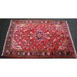 Isfahan style rug with central rosette, floral design over red ground, and triple border, 156cm x