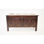 A late 17th/early 18th century oak coffer, with a four panel hinged top above a nulled frieze and
