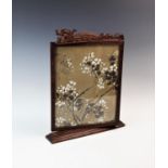 A Chinese carved wood table screen, circa 1900, of rectangular form with central glazed rotating