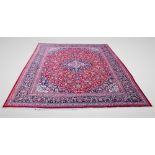 A large red ground Persian Mashad carpet, with traditional floral medallion pattern, 395cm x 295cm