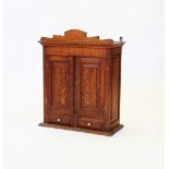 An early 20th century oak wall cabinet, with a shaped pediment above a pair of panelled doors,