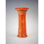 A mottled orange Ruskin vase, of cylindrical form with trumpet shaped neck, applied with a lustre