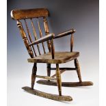 A child's elm and beech wood spindle back rocking chair, with three tapering spindles above a shaped