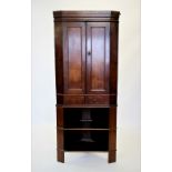 A George III and later oak corner cupboard on stand, with a moulded cornice above a pair of panelled