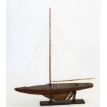 A scratch built wooden pond yacht, 20th century, with single mast and three linen sails, upon a
