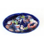 A Moorcroft oval bowl, decorated in the Anemone pattern against a cobalt blue ground, painted