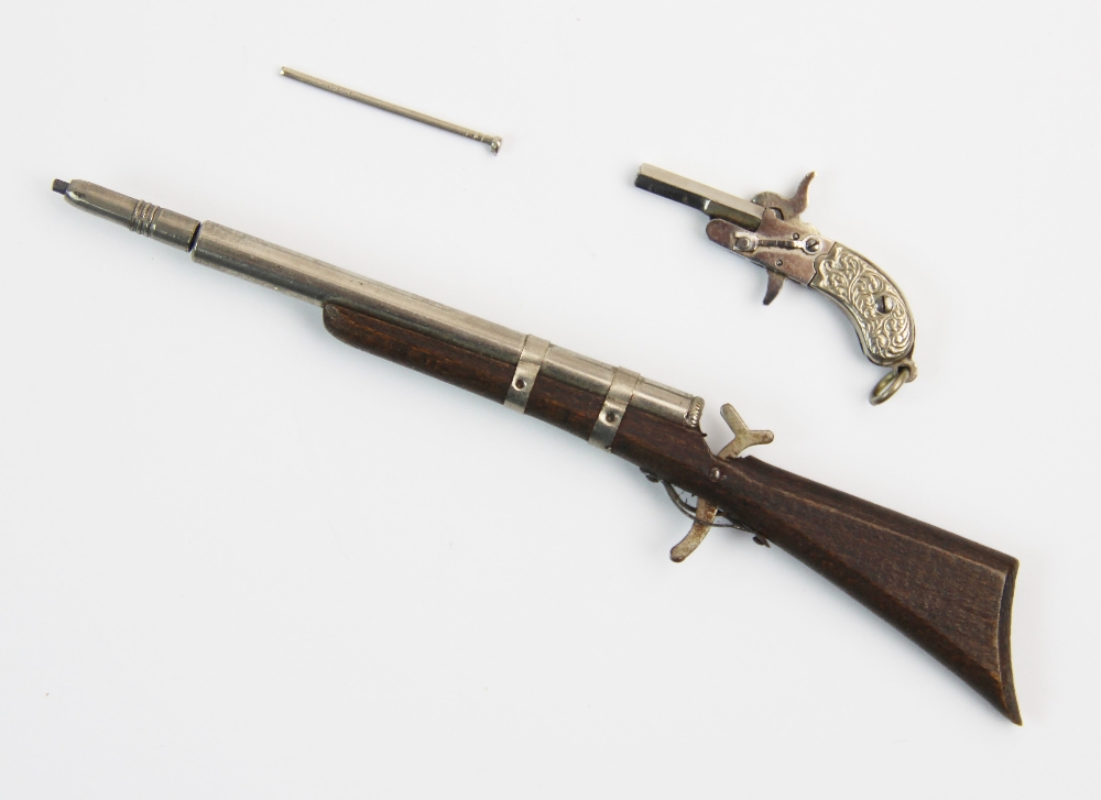 A late 19th century novelty propelling pencil, designed as a rifle, the wooden body with white metal