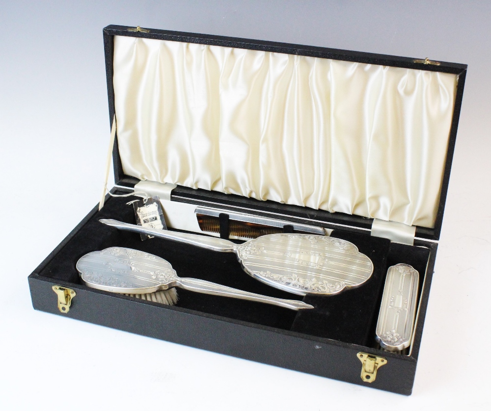 A silver backed dressing table set, W I Broadway & Co, Birmingham 1976, comprising: a hand mirror, a