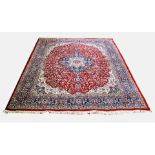 A Persian pattern wool rug, with a central circular medallion on a red trailing foliate ground,