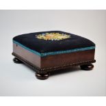 A William IV mahogany footstool, the upholstered square top centred with a needlework spray of