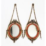 A pair of early 20th century French gilt wood pendent wall mirrors, the oval mirrored plates