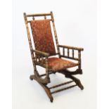 An American stained beech wood rocking chair, with a padded back and seat, raised upon a ring turned