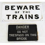Two painted metal railway signs 'Danger do not trespass on the bridge', relief cast white text on