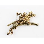 A 9ct yellow gold brooch of horse racing interest, designed as a horse and jockey with a textured