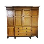 A 19th century scumbled pine breakfront wardrobe, with an over hanging cornice above a central