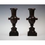 A pair of turned urn shaped candlesticks, probably lignum vitae, of baluster form with extended