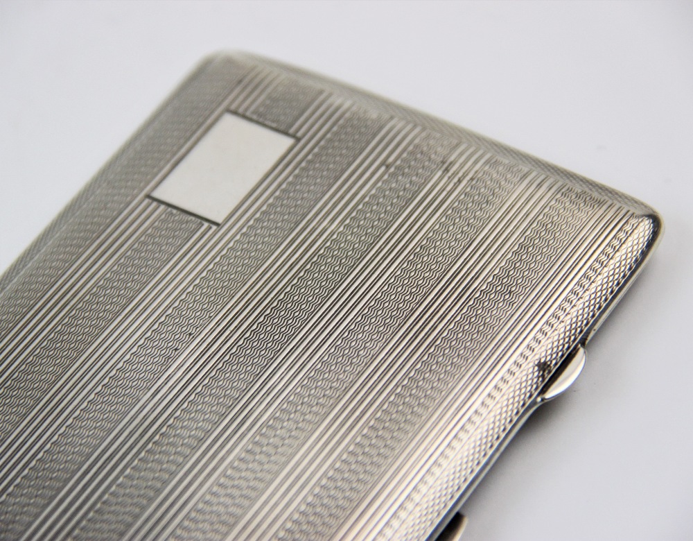 A silver cigarette case, John Rose, Birmingham 1943, of rectangular form, with striped and engine