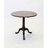 A George III mahogany tripod table, the circular tilt top raised upon a gun barrel ring turned