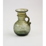 A Roman green glass jug, 3rd century AD, with spherical body and concave base, applied handle from