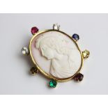 A carved shell cameo brooch with multi (untested) gem set border, the oval cameo depicting a