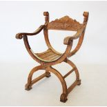 A carved walnut Italian X frame chair, the top rail carved with a scrolling foliate design,