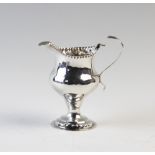 A George III silver milk jug, London 1780, of plain polished, pedestal form, with beaded rims and