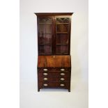 An early 19th century mahogany bureau bookcase, with a moulded tapering cornice above a pair of