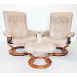 A pair of taupe leather Ekornes stressless reclining armchairs, mounted upon a stained beech wood