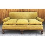 An early 20th century three seater settee, covered in embossed foliate fabric, the three fitted seat