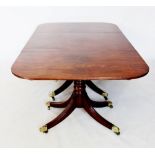 A Regency mahogany three pillar dining table, the oval top with a reeded edge, raised upon three