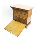 An early 20th century honey oak fall front specimen cabinet, with a moulded cornice above a plain