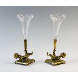 A pair of brass cherub posy holders, each modelled as a tumbling child on a cushion supporting a