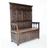 A late Victorian carved oak box settle, in the 17th century style, the high back with four panels