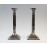 A pair of silver candlesticks, each modelled in the form of a Corinthian capital with fluted