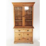 A Victorian pine bookcase on chest, with a moulded cornice above a pair of glazed doors enclosing