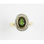 A peridot and diamond cluster ring, designed as a central oval peridot, collet set in yellow gold,