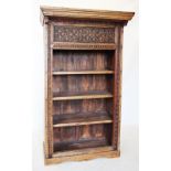 An Indian carved hardwood open bookcase, the deep frieze carved with stylised flower heads above
