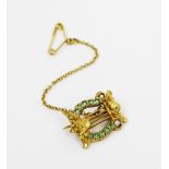 An emerald and seed pearl set lyre form brooch, all set in yellow metal, unmarked, attached safety