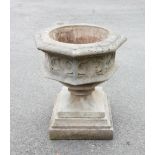 A reconstituted stone Gothic urn, of octagonal form the sides cast in deep relief with