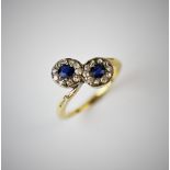 A sapphire and diamond double cross-over ring, designed as two sapphire and diamond clusters, within